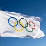 STUNNING Betrayal: Olympian TURNS on Women’s Sports Olympic flag waving against clear blue sky.