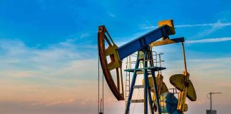 An oil pump jack operating against a sunset backdrop