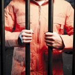 SHOCKING Abuse of Office — He Called From JAIL Person in an orange jumpsuit gripping prison bars in a dark cell