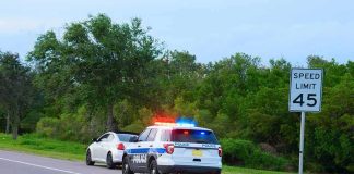 Roadside Drug Tests WRONG 38% — Convicting Innocent Police car with flashing lights pulling over a white vehicle beside a speed limit sign