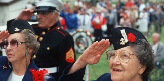 Elderly women in military attire saluting during a veterans ceremony