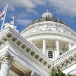 Congressman Threatens Reporter With GUN! Capitol building dome and flags under a blue sky.