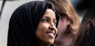 A woman wearing a black hijab smiling at an outdoor event