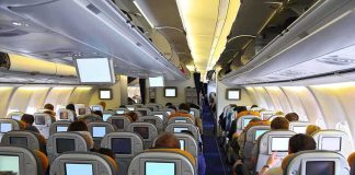 Airline Passenger DISGUST: Toenails Everywhere! Interior view of an airplane with passengers seated and using in-flight entertainment screens
