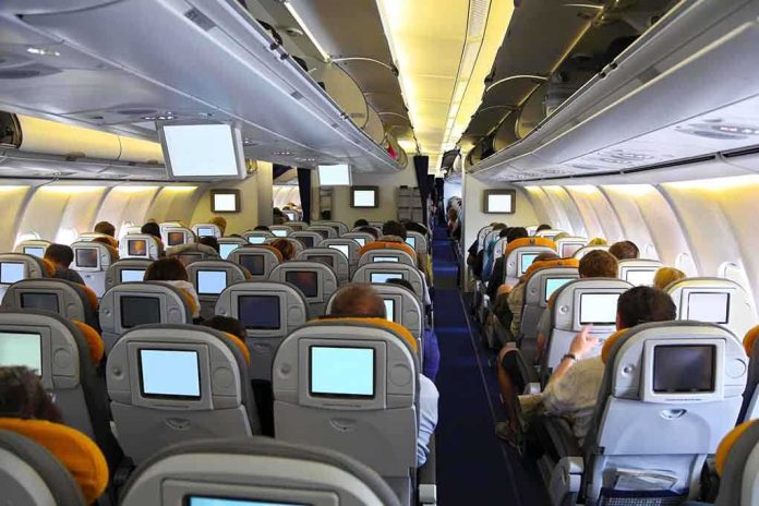 shutterstock_142431973 Interior view of an airplane with passengers seated and using in-flight entertainment screens