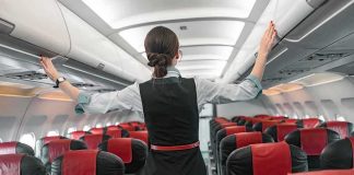 Flight attendant checks overhead bins in empty airplane cabin