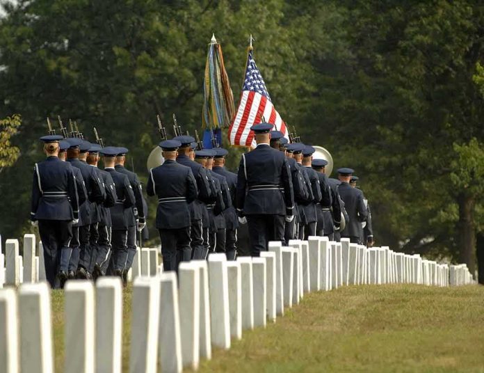 shutterstock_4258348 Military honor guard marches through a cemetery with flags