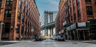 Kids Hustling Goods Across U.S Cities—Where Are Cops? Street view with bridge between two brick buildings.