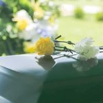 Yellow rose and white carnation on a green casket