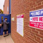 Voters line up outside a brick building polling place