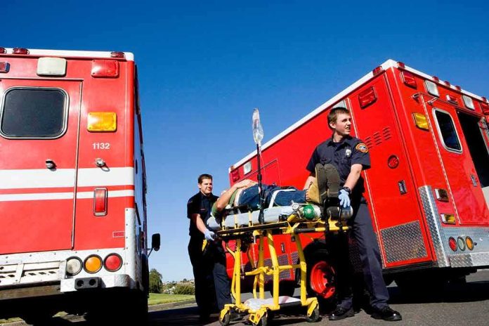 Paramedics move a patient on a stretcher between red ambulances