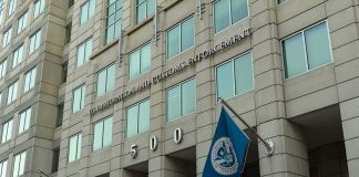 U.S. government building facade with American and blue departmental flags