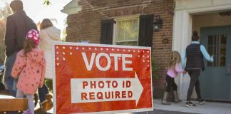 GOP Loses 30-Year Stronghold Seat Red voting sign with arrow near people entering a polling place