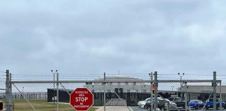 Small Cages Found Outside ICE Detention Center Chain-link fence with Restricted Area Stop No Photography sign.
