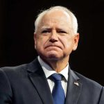 Walz Admits He Let State Get Looted Tim Walz in a dark suit and tie at an event