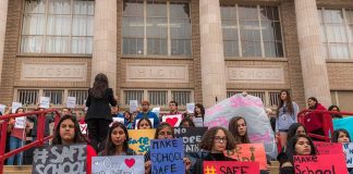 Students holding protest signs on school steps