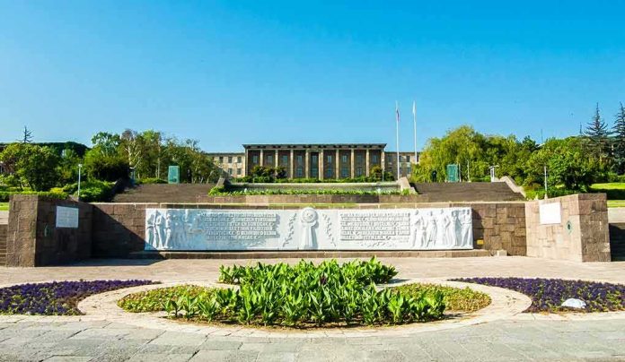 shutterstock_1050595889 Government building behind landscaped gardens and a stone relief wall