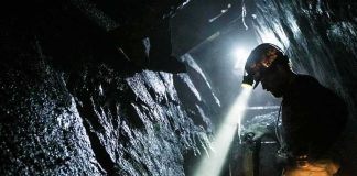 miner with headlamp working in a dark tunnel