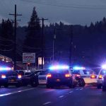 Manhunt Erupts – Maniac Guns Down Police Police cars with flashing lights block a road at night
