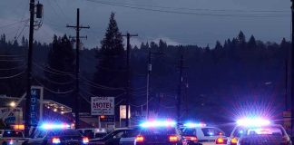 Police cars with flashing lights block a road at night