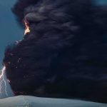 Volcanic eruption with dark ash plume and lightning