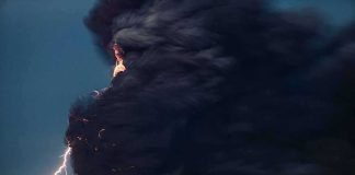 Volcanic eruption with dark ash plume and lightning
