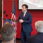 Speaker in a navy suit addressing an audience at a podium