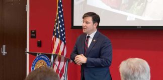 Speaker in a navy suit addressing an audience at a podium