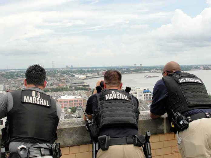 Three U.S. Marshals in tactical vests overlooking a city and river