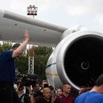 Group of people gathered near a large airplane engine