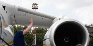 Group of people gathered near a large airplane engine