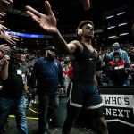 Basketball player in arena high-fives fans while wearing headphones