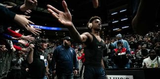 Basketball player in arena high-fives fans while wearing headphones