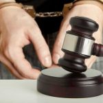 Handcuffed person behind judge's gavel