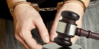 Handcuffed person behind judge's gavel