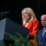 Jill Biden speaks at a podium as Joe Biden stands behind her