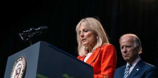 Jill Biden speaks at a podium as Joe Biden stands behind her