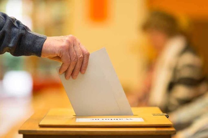 Hand placing a ballot into a wooden voting box