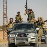 armed men riding on pickup trucks in a convoy