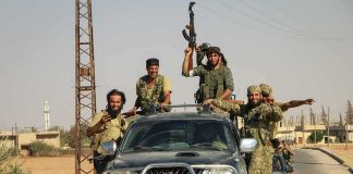 armed men riding on pickup trucks in a convoy
