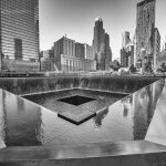 A memorial water feature surrounded by tall buildings in a city
