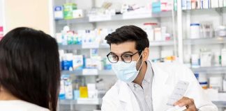 Pharmacist wearing mask explains medication to customer