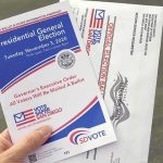 Radical Far-Left Afghani Wins US House Special Election Hand holding election pamphlet and mail-in ballot envelopes