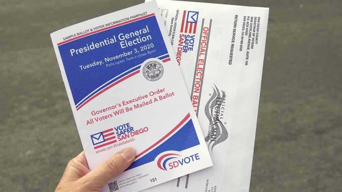 Hand holding election pamphlet and mail-in ballot envelopes