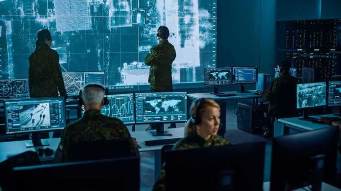 Military analysts monitor data on multiple screens in a command center