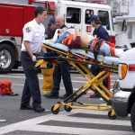 Gary Patterson on a stretcher being moved by paramedics near fire trucks and an ambulance