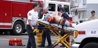 Gary Patterson on a stretcher being moved by paramedics near fire trucks and an ambulance