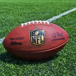 NFL Star Mawls Ballboy – Sideline Stunned! American football on a turf field near a white yard line
