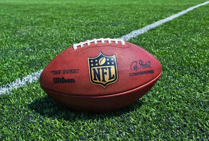 shutterstock_205708945 American football on a turf field near a white yard line