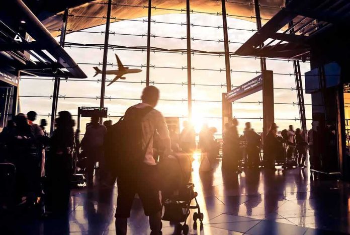 shutterstock_210042955 Airport terminal crowd at sunset with airplane silhouette outside